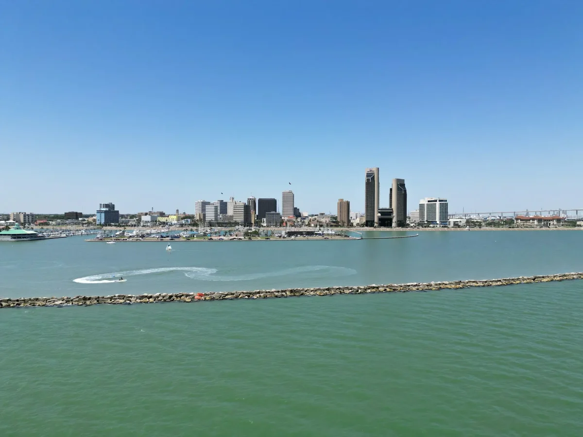 Ocean with breakwater in center and city skyline in background.